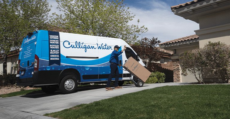 Delivery man wheeling a Culligan product up a driveway
