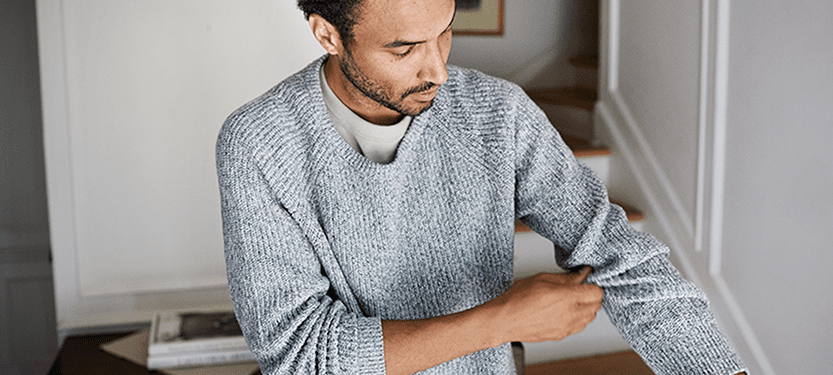 Man pulling on a soft sweater washed in water from a Culligan Whole Home System